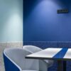 Comfortable armchairs at white table placed near blue wall in modern small workspace with stylish design in contemporary business center